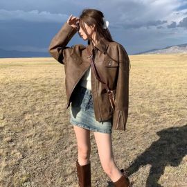 جاكت جلدي قصير وفضفاض بتصميم يتميز بأزرار كبس، وخصر مطاطي، وأكمام منفوخة مع سحاب عند الأطراف